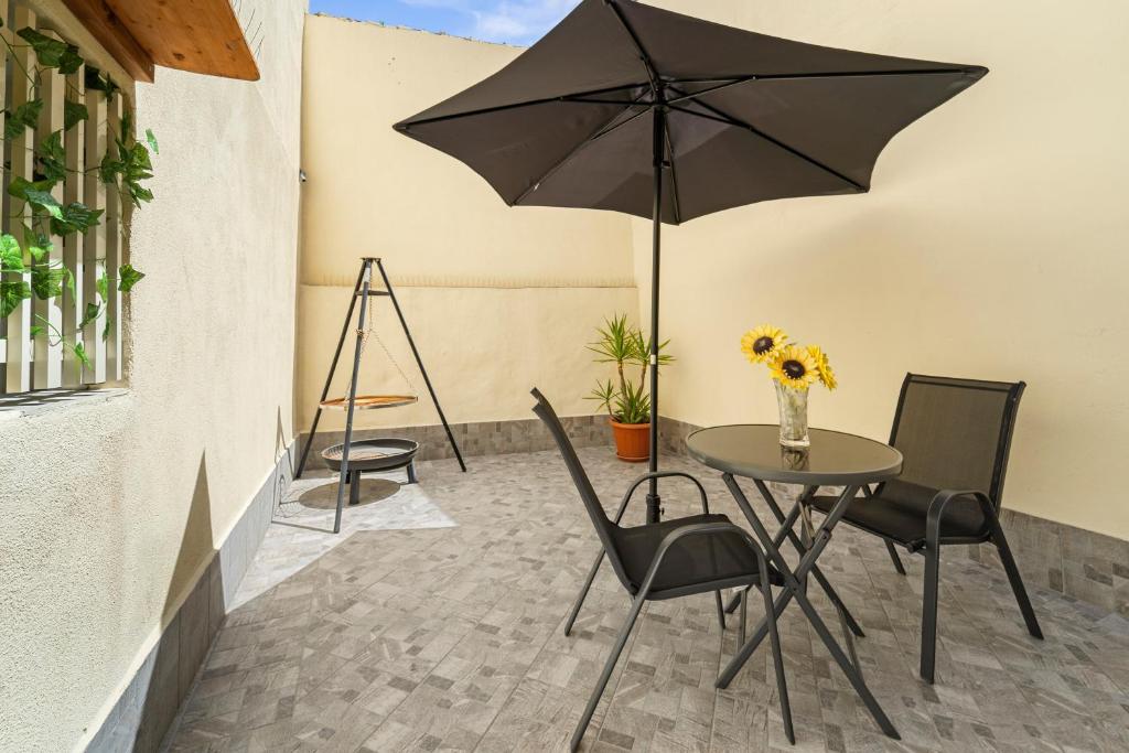 a table with chairs and an umbrella on a patio at Casa Vacanze Sa Domixedda in Guspini