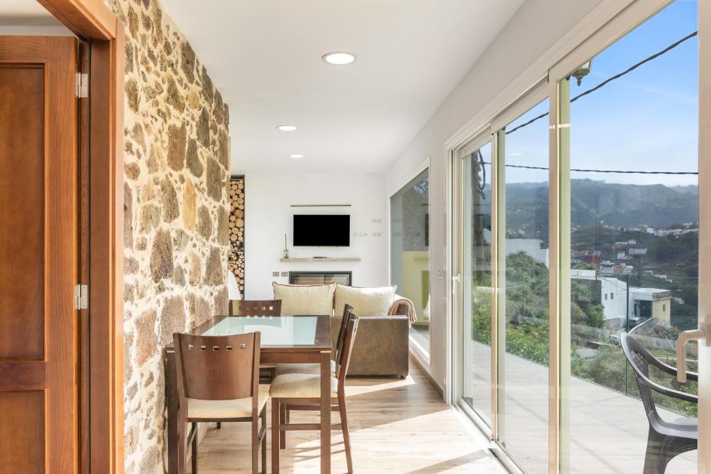 a dining room with a stone wall and a table and chairs at Casa Eloisa in Teror