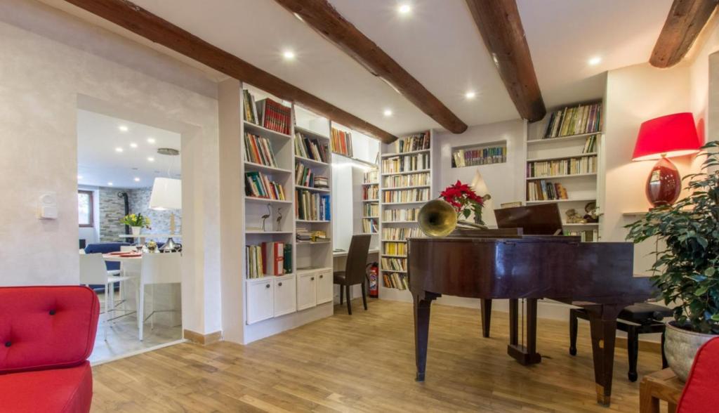 a living room with a piano and bookshelves at Le Clos Savoie Lorraine in Thônes