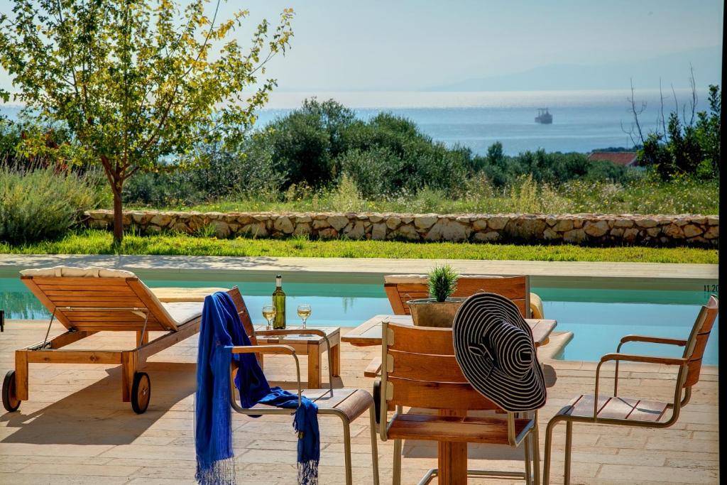 a patio with chairs and a table and a pool at Villa Ippokampos Ideales Resort in Kefallonia