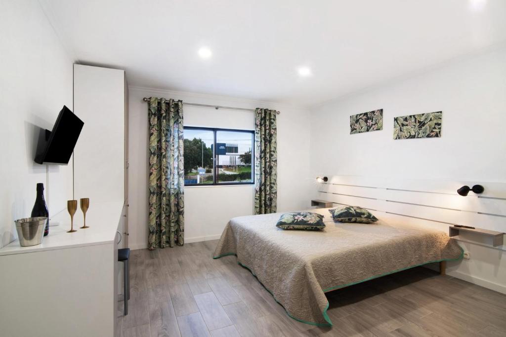 a white bedroom with a bed and a window at Apartamento nº3 - Familiar in Moncarapacho
