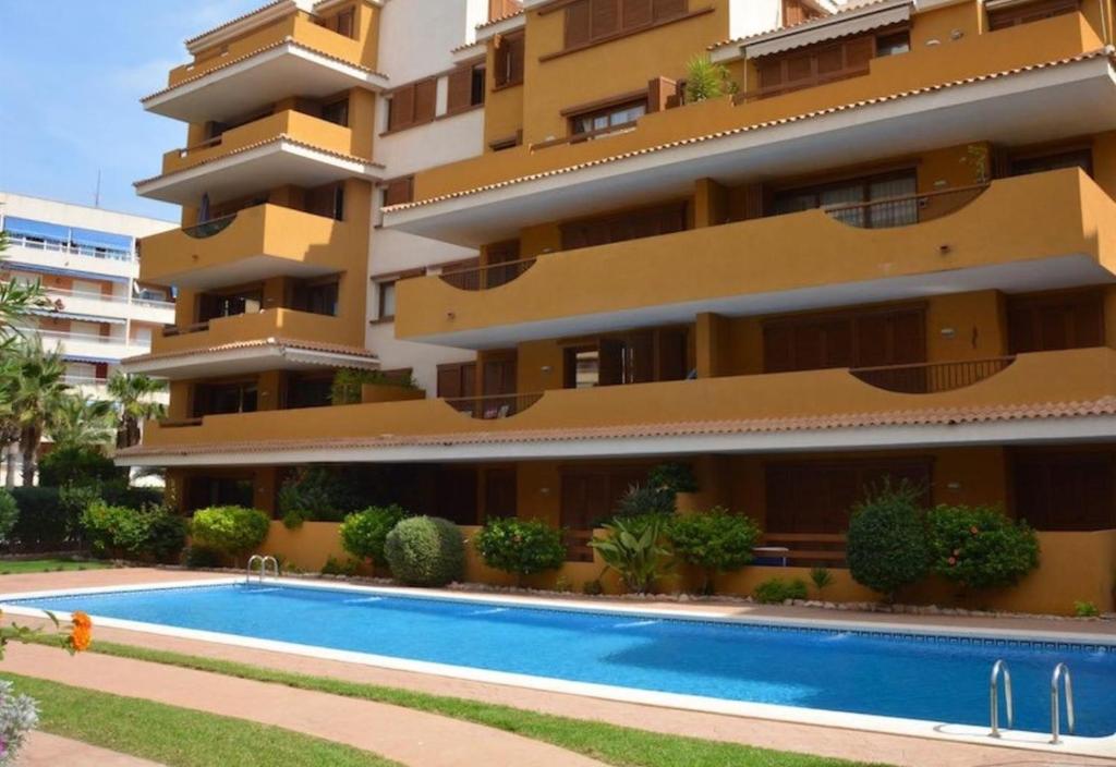 a building with a swimming pool in front of it at Spacious ground floor apartment in Punta Prima