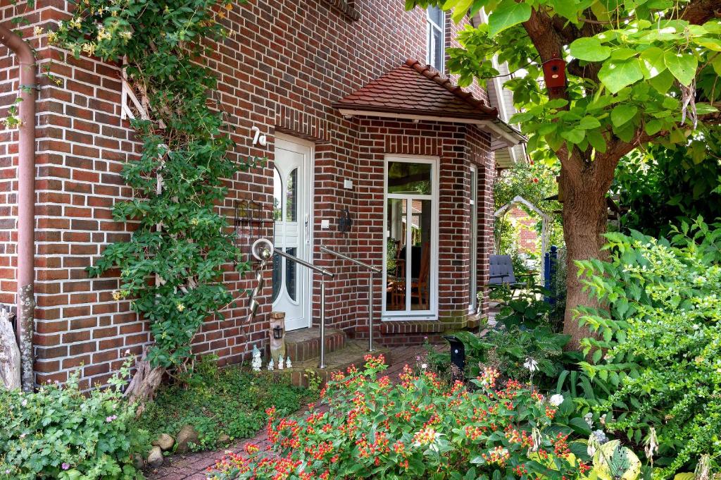 a brick house with a white door and some flowers at Inge Huus in Hude