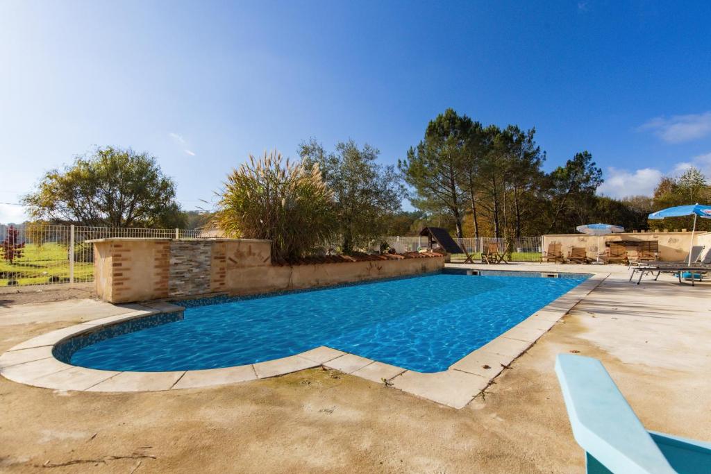 a large swimming pool in a yard with a blue at Le Moulin in Guizengeard