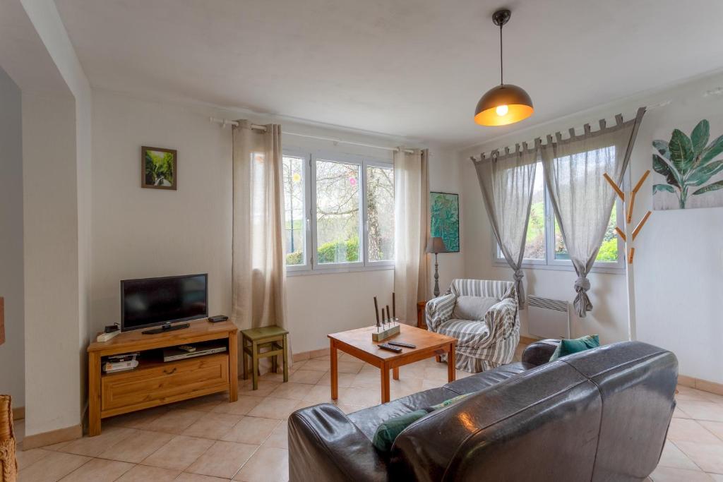 a living room with a couch and a tv at Maison de vacances Camille in Artigues