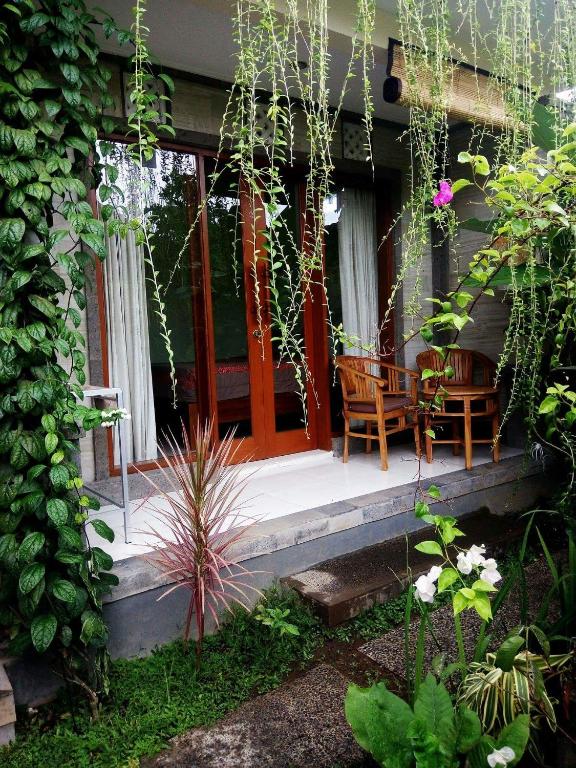 a porch of a house with two chairs and a table at Sudiana House in Ubud
