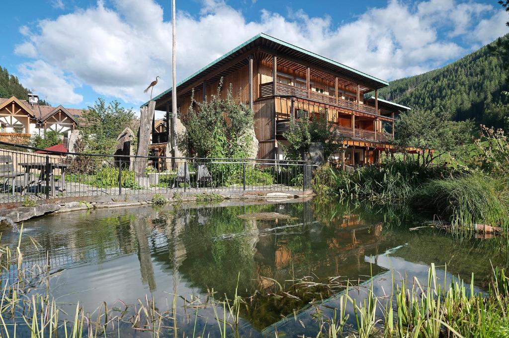 a log house with a pond in front of it at Naturidyll Mitterbach in Rio Bianco