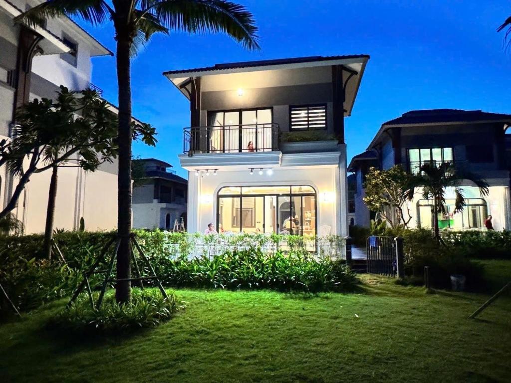 a large white house with a palm tree at V3K03 Sonasea Vân Đồn in Thâm Câu