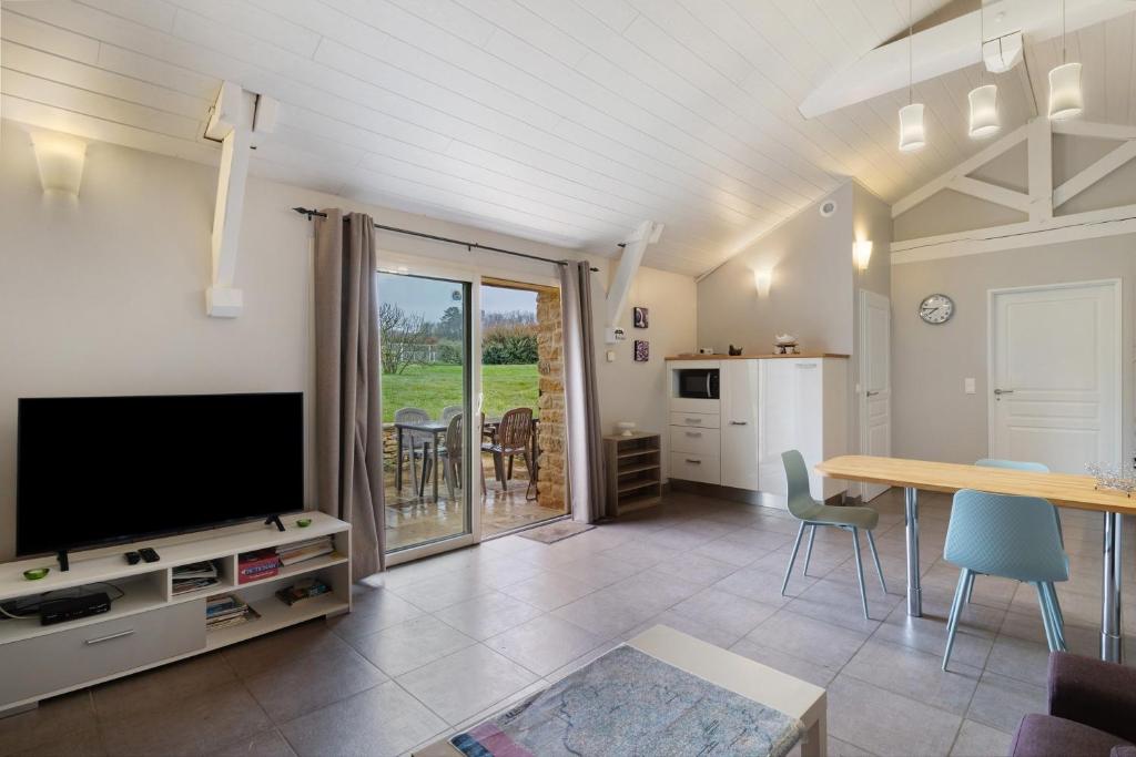a living room with a flat screen tv and a table at La Cense De La Mérelie - Le Logis in Saint-Geniès