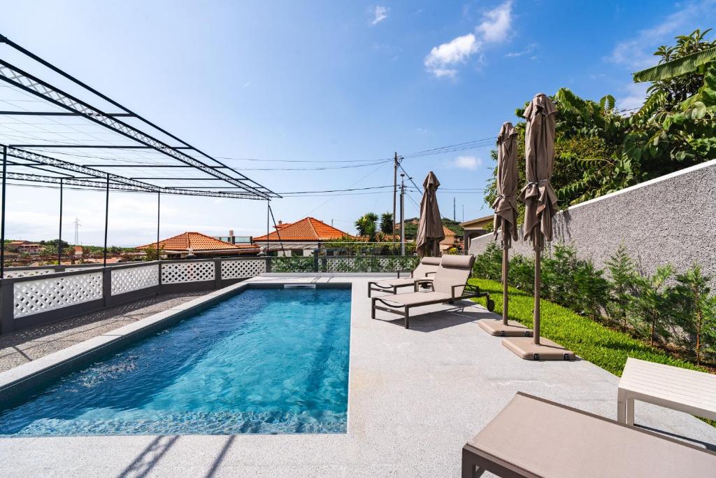 a swimming pool with umbrellas next to a building at Solar do Ilheuzinho in Câmara de Lobos