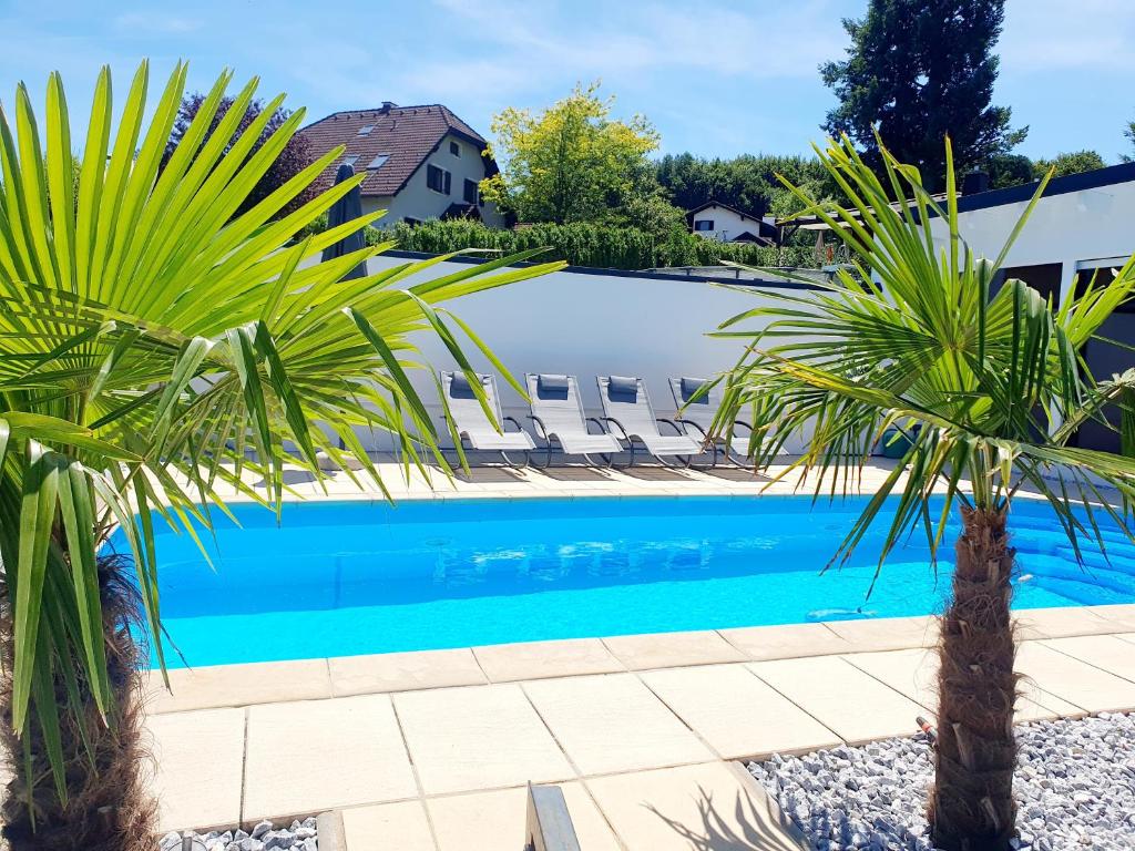 a swimming pool with two palm trees and lounge chairs at Luxury Villa Vienna in Mauerbach