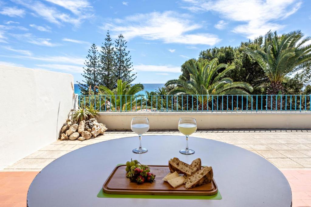 a table with a plate of food and two glasses of wine at Formosa Beach in Porto Santo
