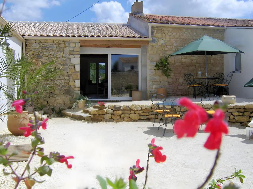 a house with a patio with a table and an umbrella at Chambres D'hôtes La Marouette in Hiers-Brouage