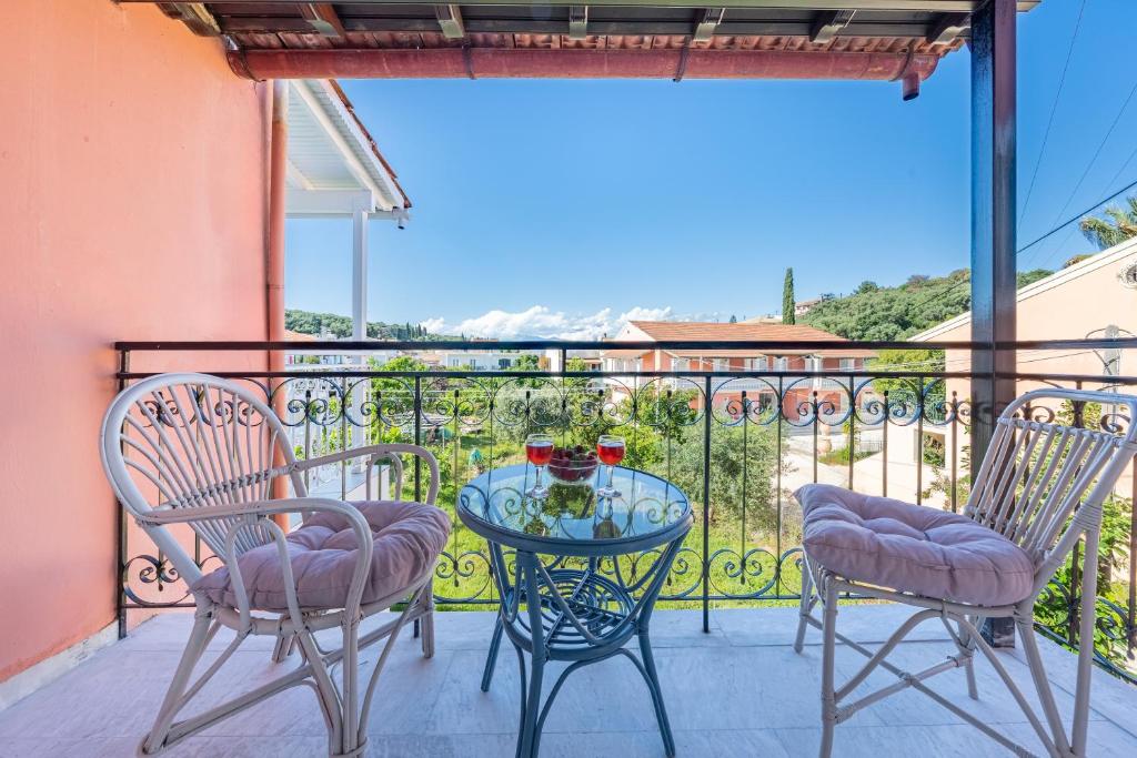 a patio with two chairs and a glass table on a balcony at Kassiopi Apartment 2 in Kassiopi