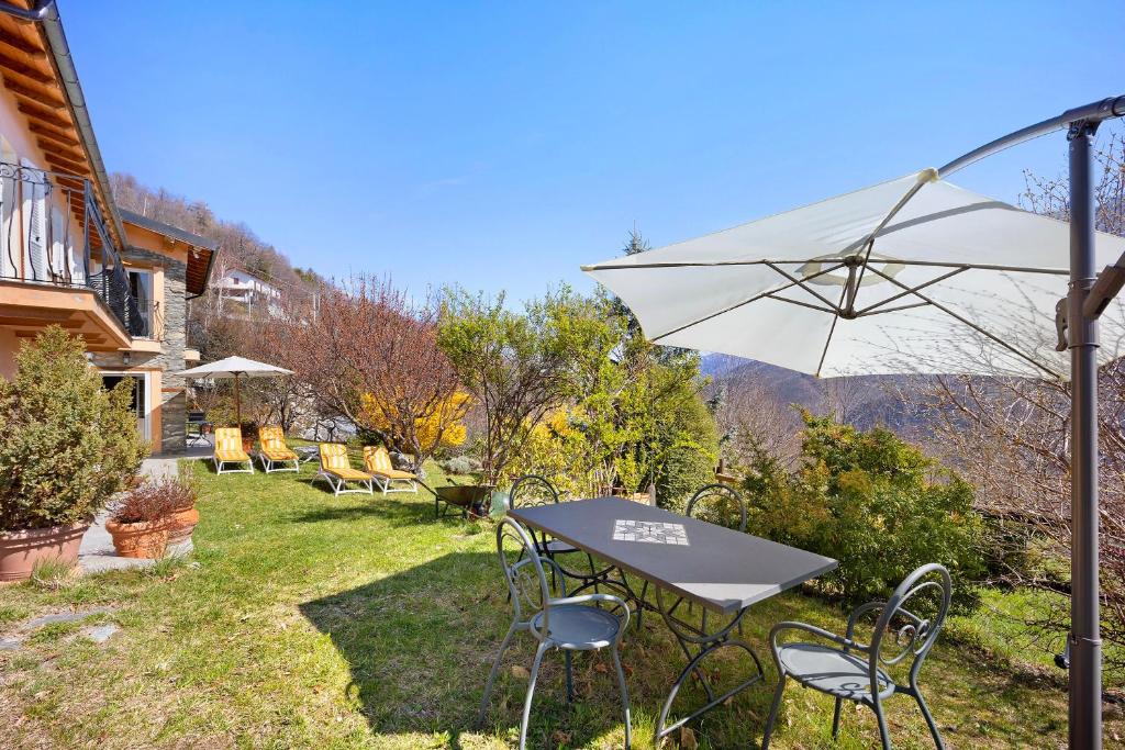 ein Tisch und Stühle mit einem Sonnenschirm im Gras in der Unterkunft Casa dei Tigli in Ormea