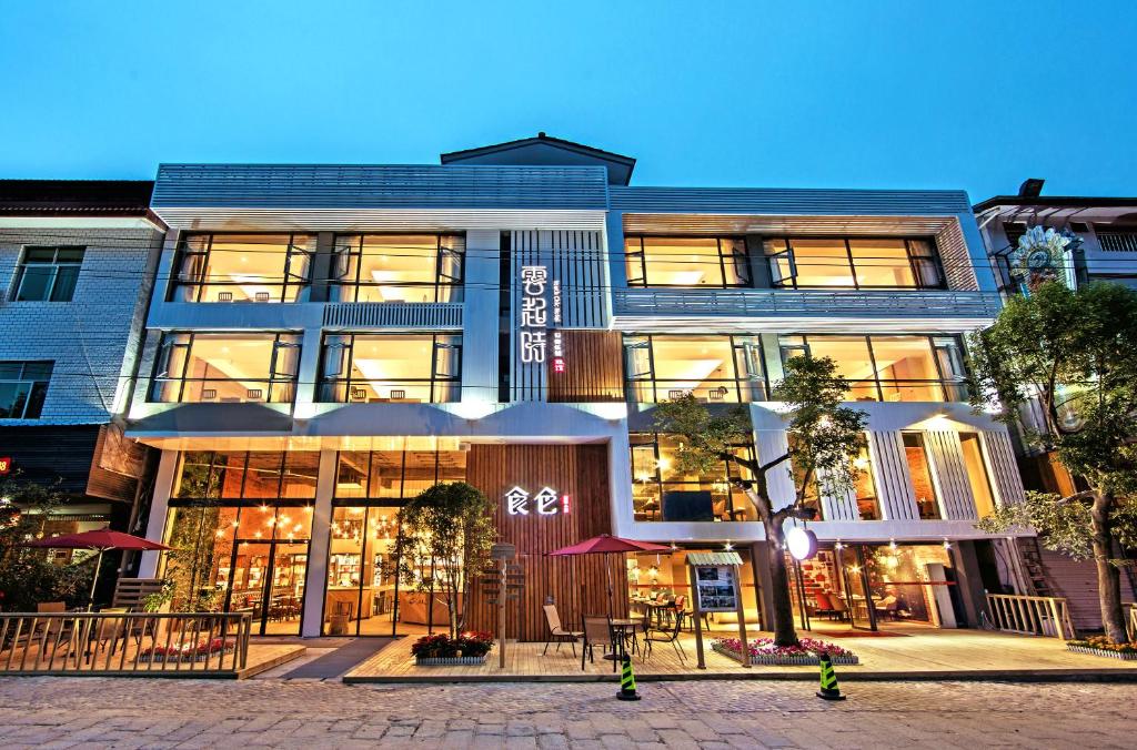 a large building with tables and chairs in front of it at Ancient Street No.5 Youth Chic Hotel in Wuyishan