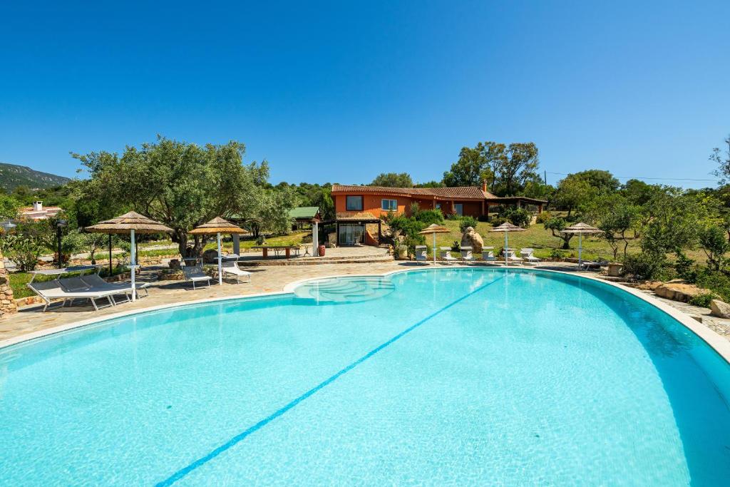 a large swimming pool with chairs and umbrellas at Harmònia Residence in Villasimius