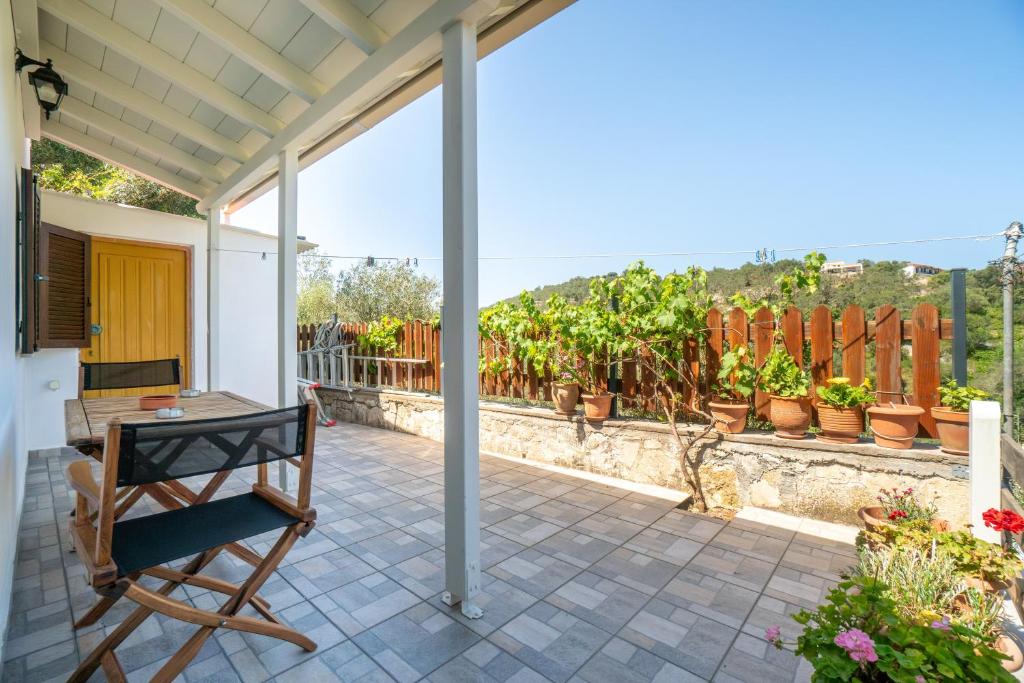 a patio with a table and chairs and potted plants at Captain Spiros Picola in Gaios