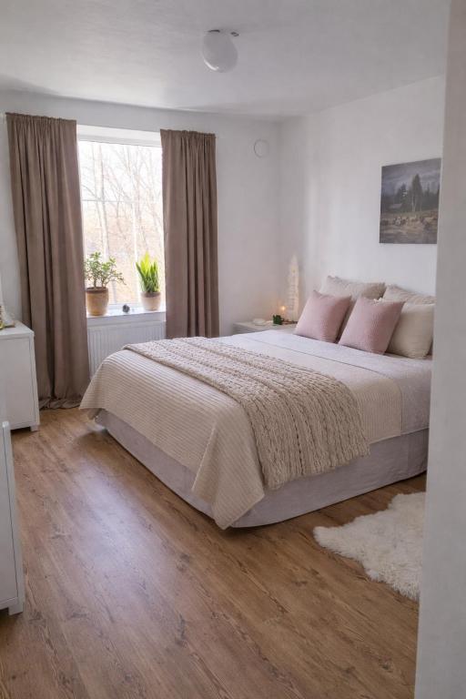 a white bedroom with a large bed with pink pillows at Maria Isabelles boende nr 3 in Fjugesta
