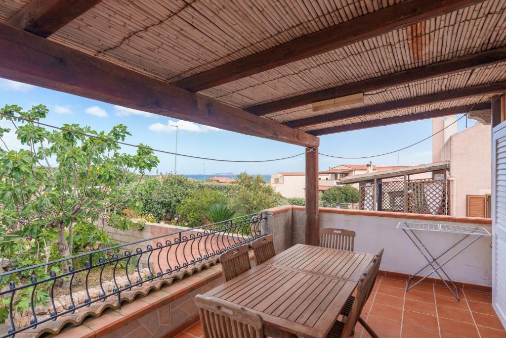 a balcony with a wooden table and chairs on it at Villa Alfredo Golfo Aranci in Golfo Aranci