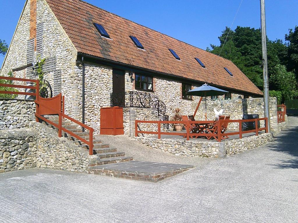 a stone building with a table and an umbrella at Cider Cottage - near Lyme Regis in Axminster