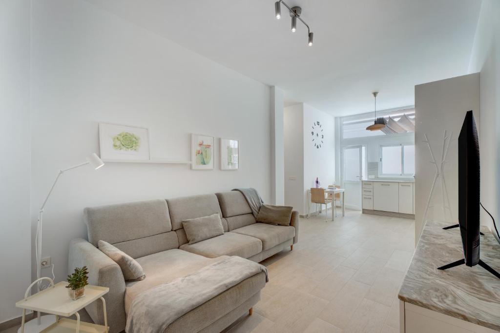 a white living room with a couch and a tv at Serenity in Arona