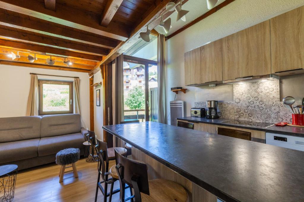 a kitchen with a counter top and a living room at Appartement Manigod Merdassier 8 p in Manigod