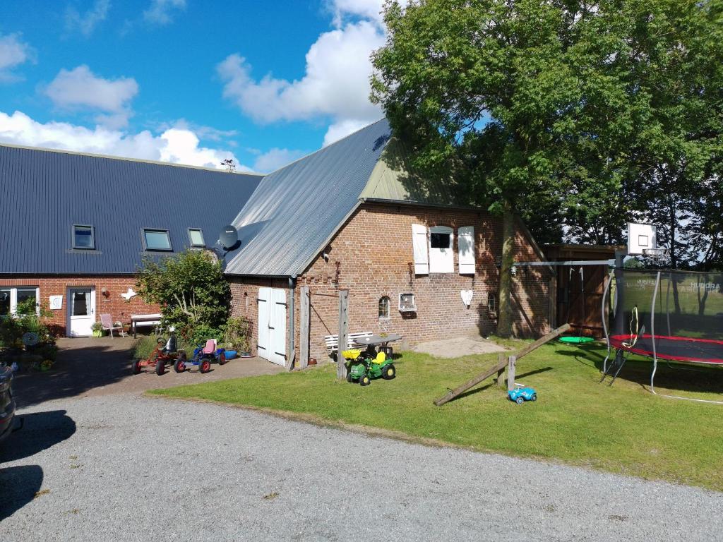 a brick building with a yard with a playground at Ferienwohnungen Sterdebüll-Hof in Bordelum