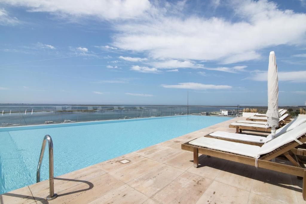 a swimming pool with lounge chairs and an umbrella at Mare Nostrum in Olhão