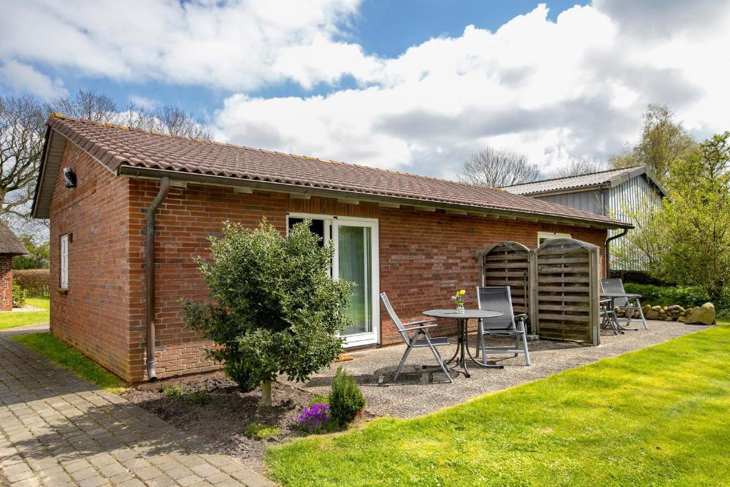 a small brick house with a table in a yard at Apartment Eulenhof 1 in Bordelum