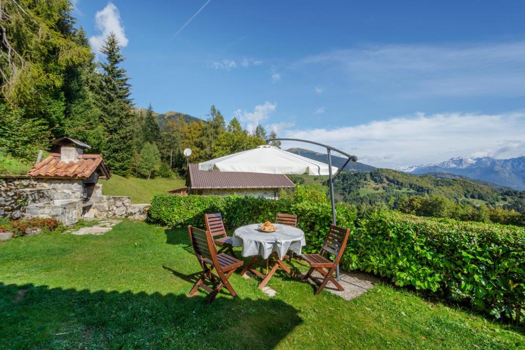 a table and chairs in a yard with mountains at Baita Nido tra i Monti in Daone