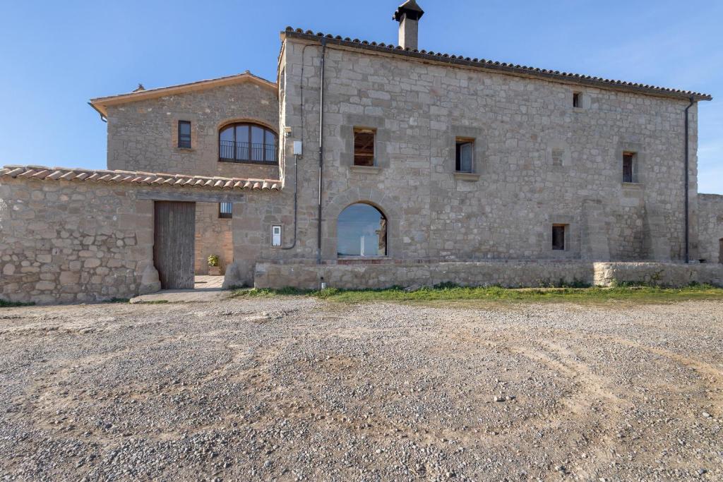 an old stone building with a dirt road in front of it at Cal Cirera in Sagás
