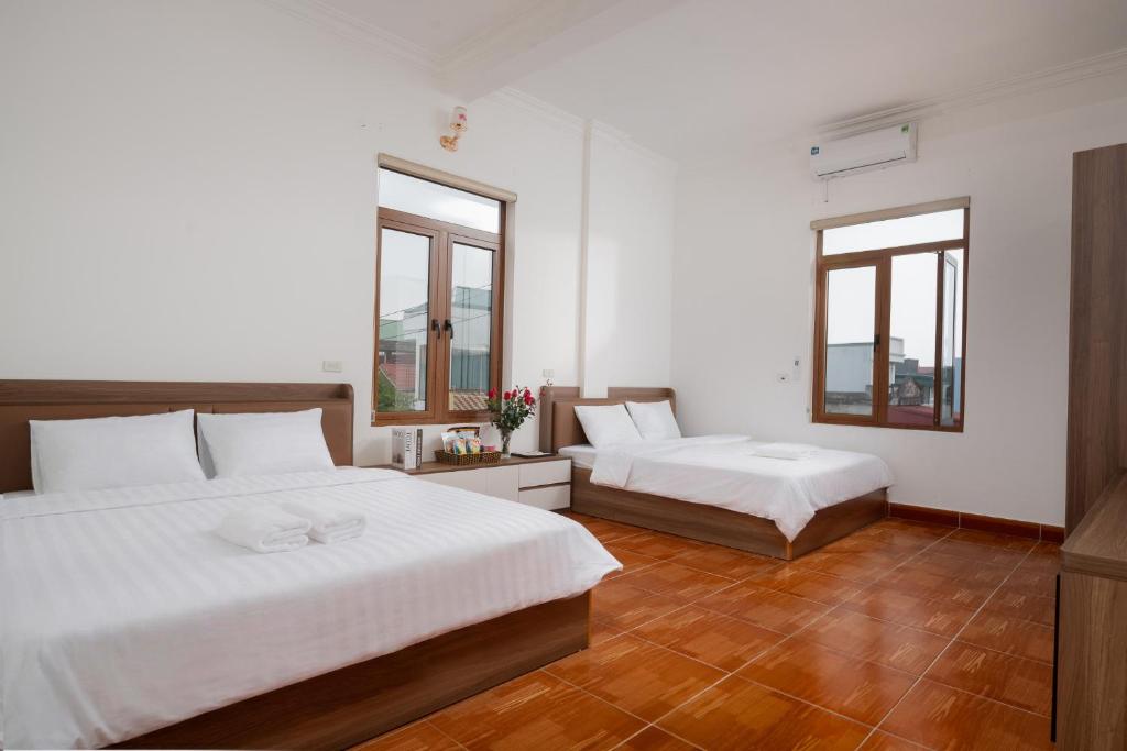 a bedroom with two beds and two windows at South Star Hotel in Ninh Binh