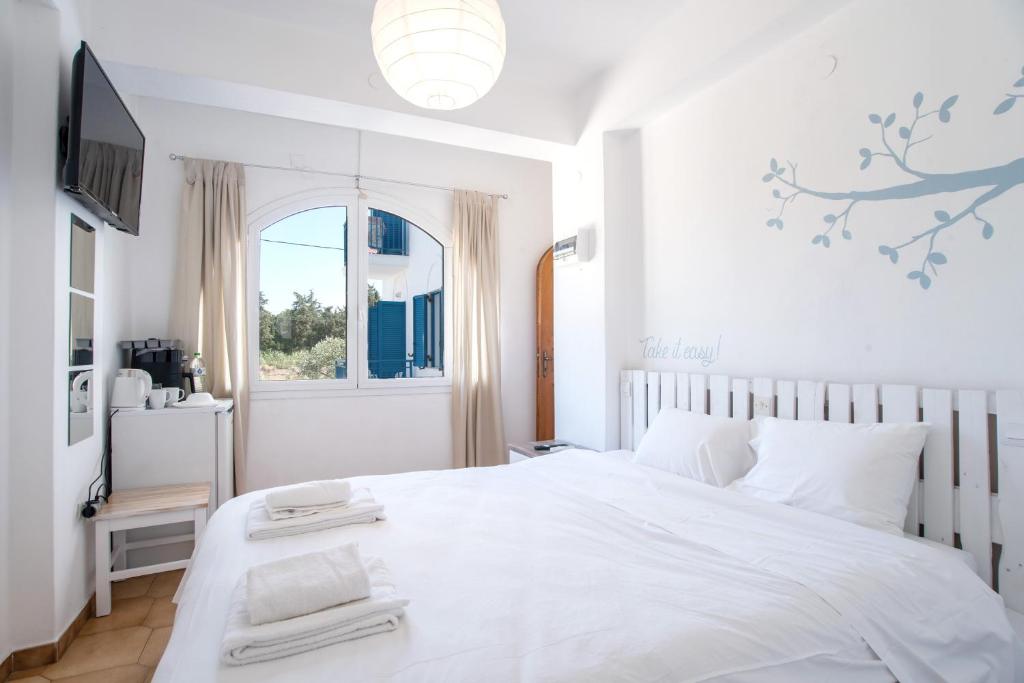 a white bedroom with a large white bed and a window at Livadia Seaside Studios 8 in Parikia