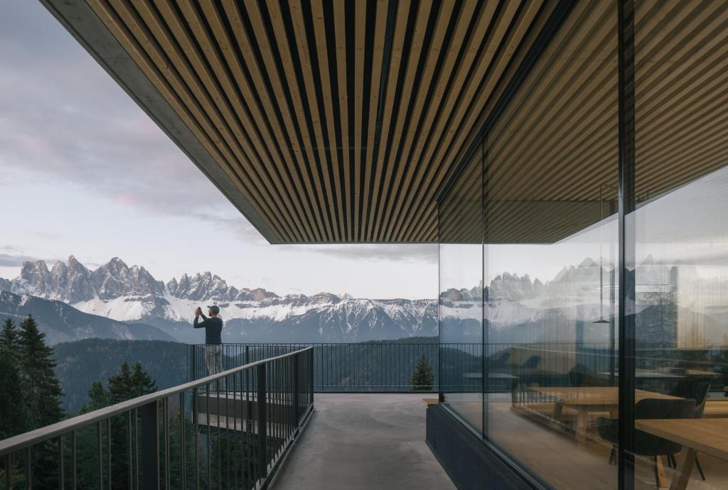 a person taking a picture of a mountain view from a balcony at anders mountain suites 6 in Brixen