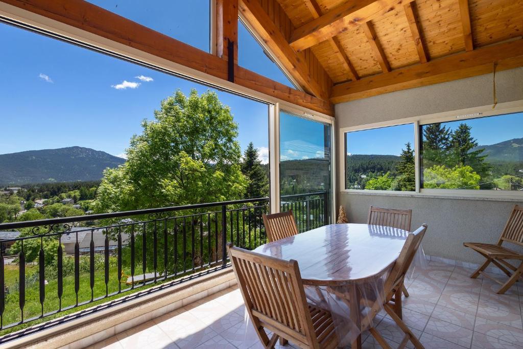a dining room with a table and chairs on a balcony at Le Calmadou in Formiguères