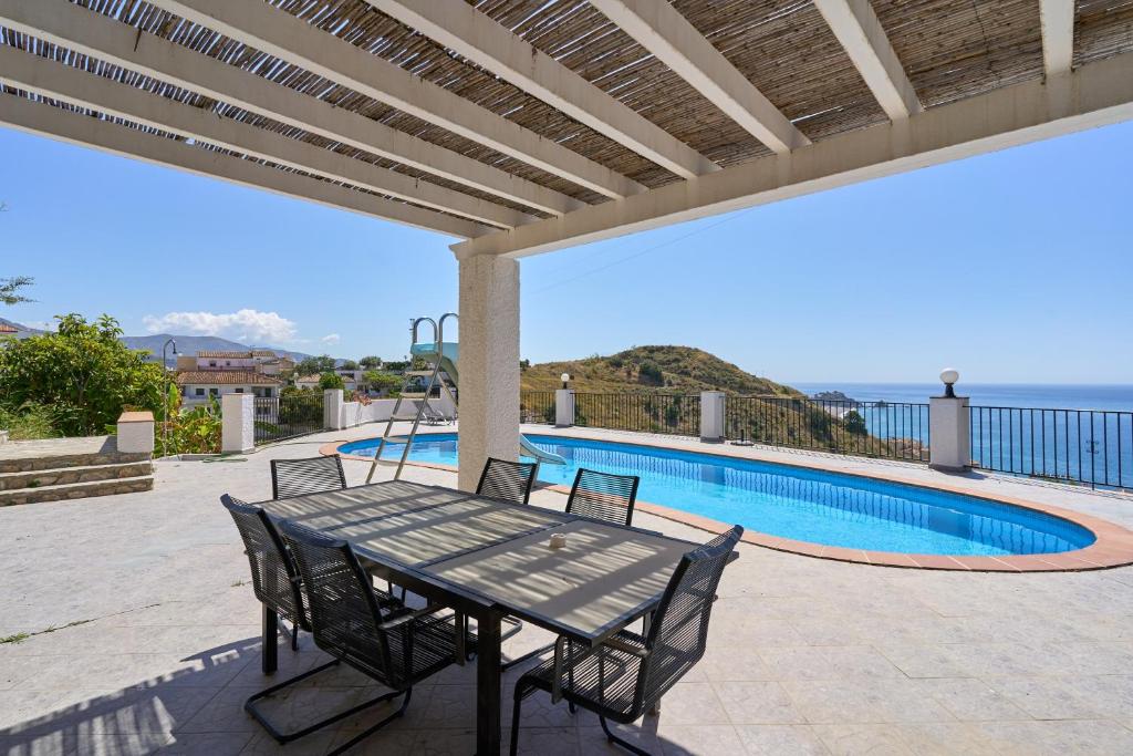 a patio with a table and chairs next to a swimming pool at Casa Beto in Almuñécar