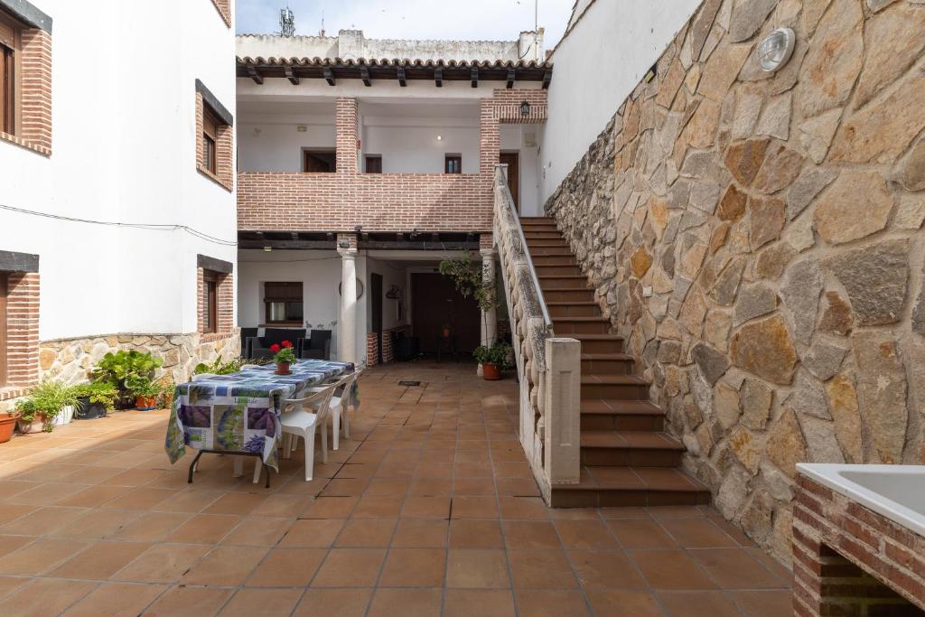 a patio with a table and a stone wall at Casa Rural La Abubilla in Valdelaguna