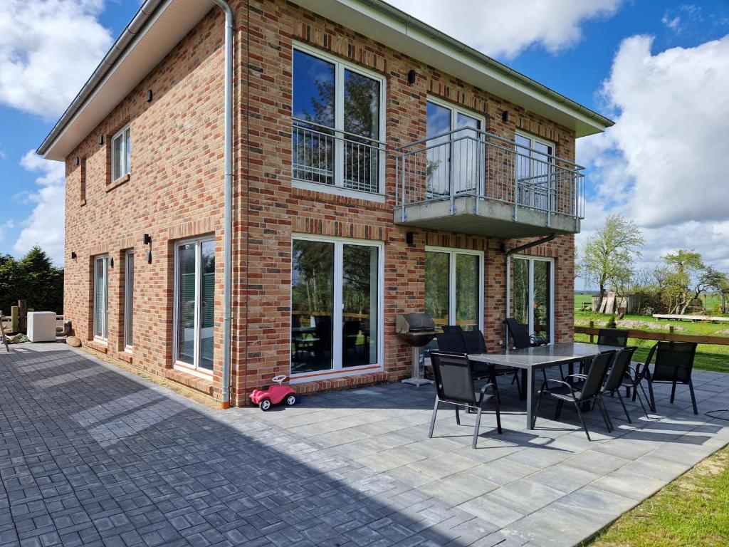 a brick house with a patio with a table and chairs at Ferienhäuser Ebbe und Flut in Schülp
