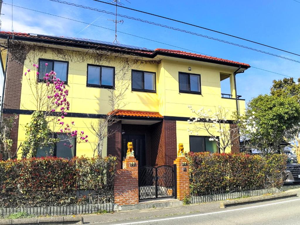 a yellow house on the side of a street at 温泉郡宿 in Toon