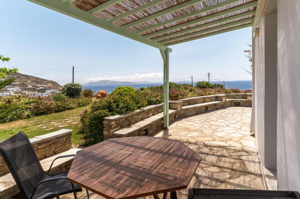 a patio with a table and chairs and a view of the ocean at Anemologio 101 Tinos in Agios Ioannis