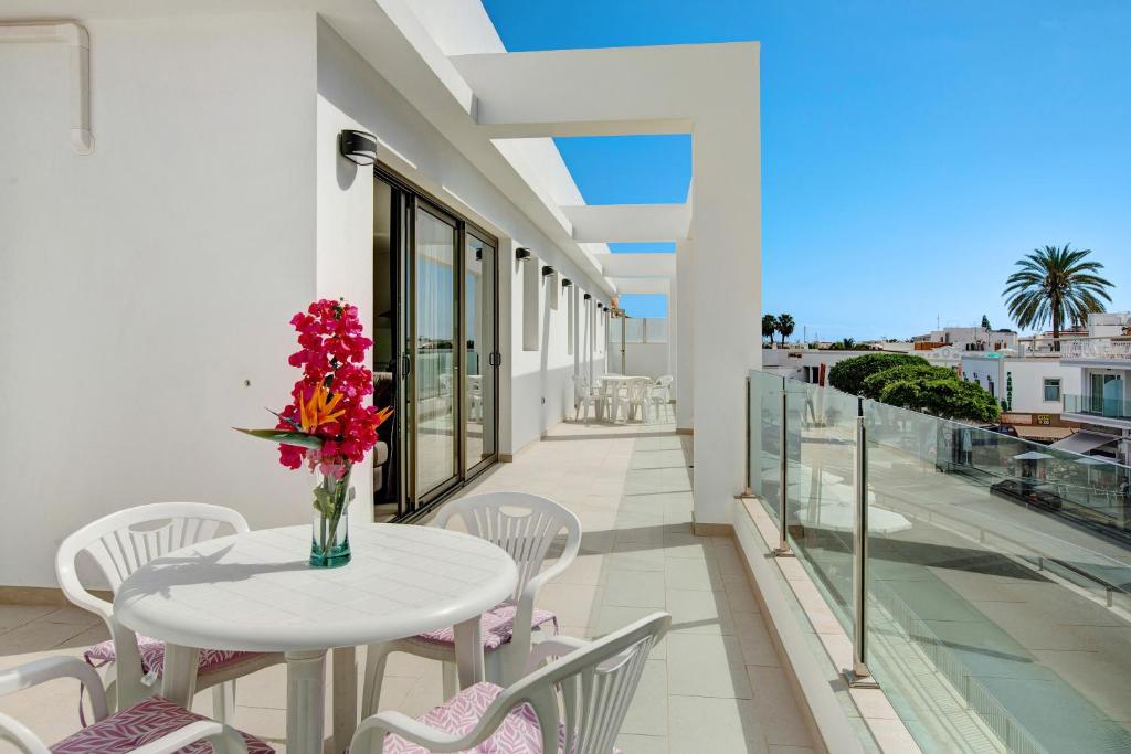a white table and chairs on a balcony with a table and flowers at Atico Albamar in Puerto de Mogán