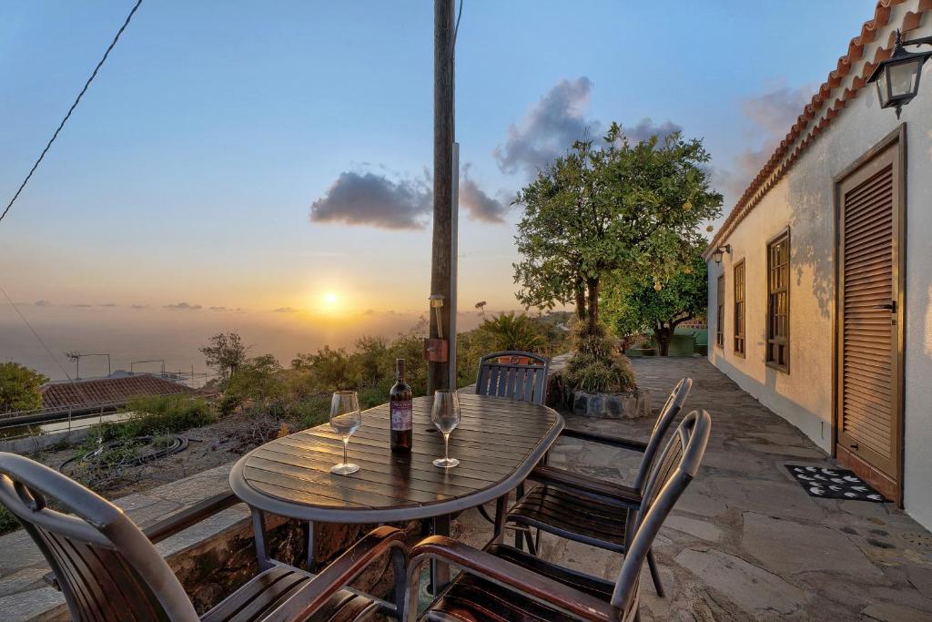a wooden table and chairs on a patio with the sunset at Casa El Naranjo Viejo in Tijarafe