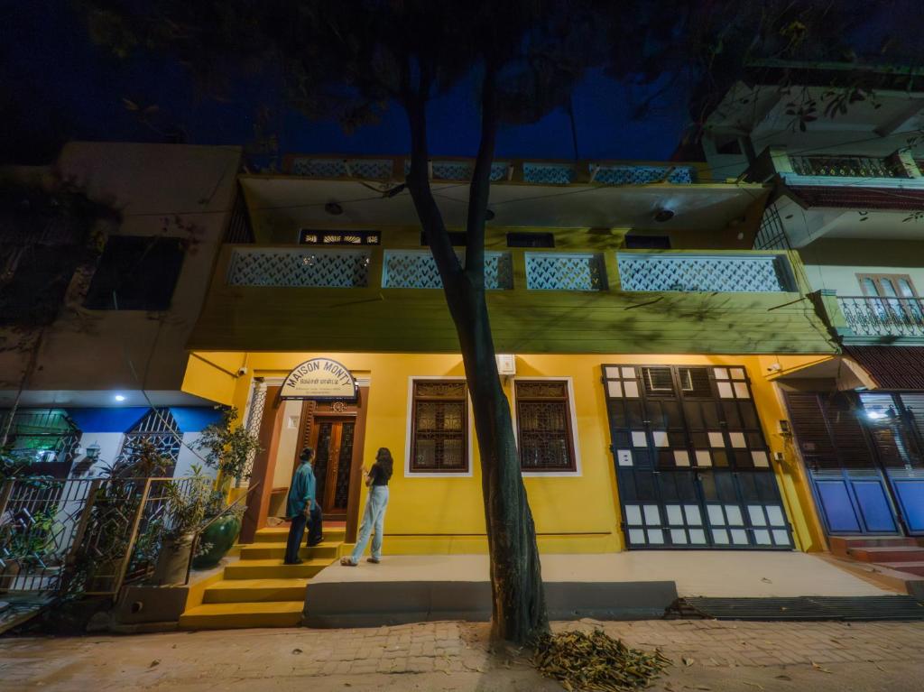 two people standing outside of a yellow building at night at Maison Monty in Pondicherry