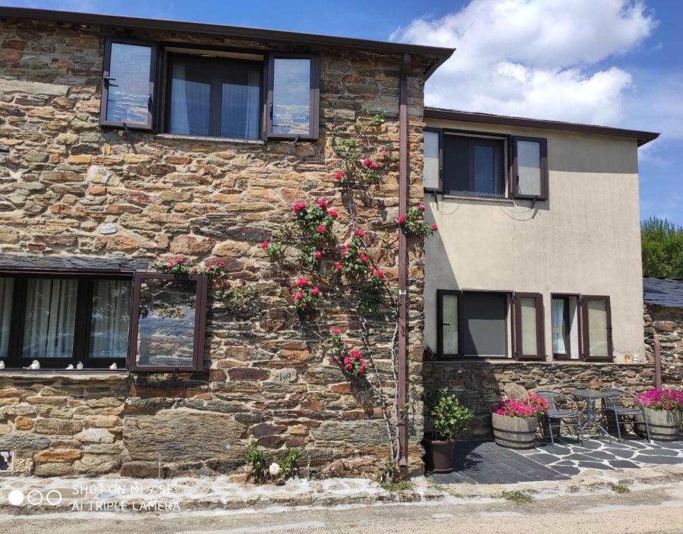 a stone house with flowers on the side of it at O Bolaño Apt 1 in Villarino de Conso