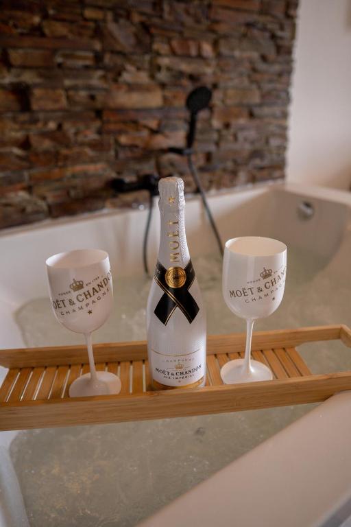 a bottle of champagne and two wine glasses on a bath tub at Luxus Appartement mit Panoramablick in Sinsheim