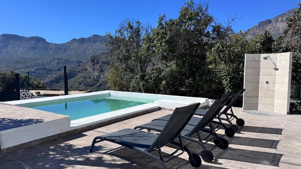 a pair of chairs sitting next to a swimming pool at Palmeral de Taidía in Taidía