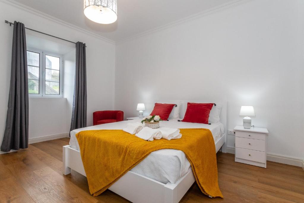 a white bedroom with a bed with a yellow blanket at Oásis Fonte Grande in Santo António