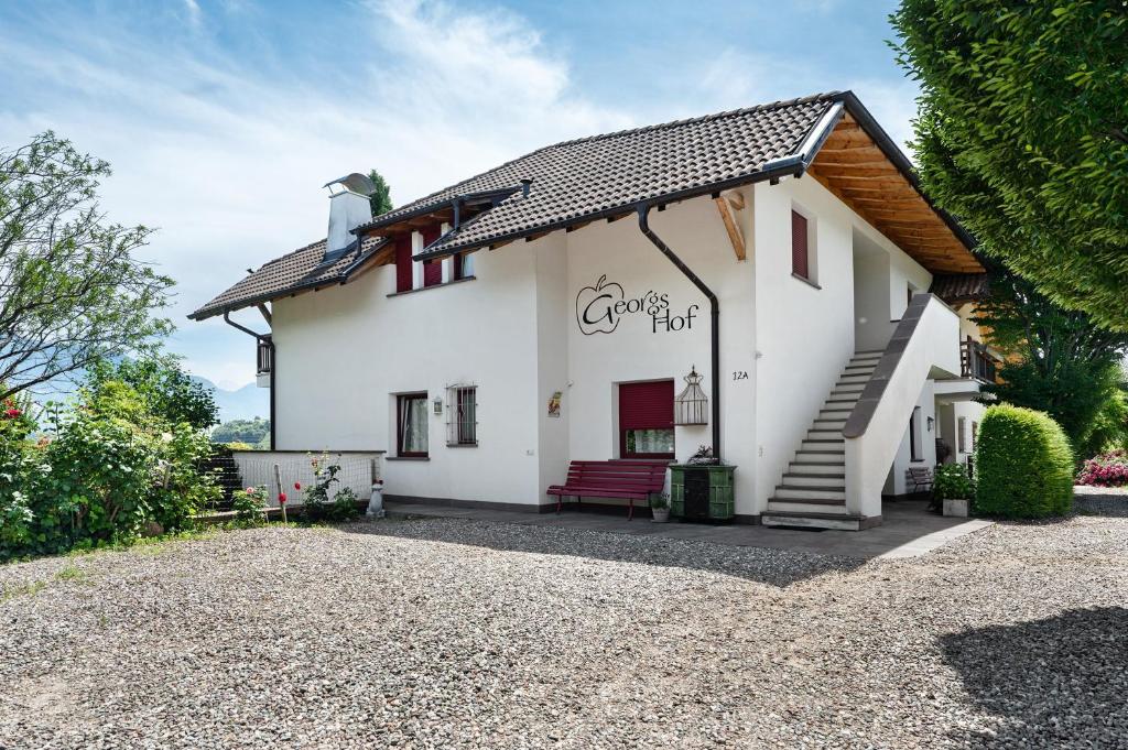a white house with a red bench in front at Georgshof - Eppan in Appiano sulla Strada del Vino