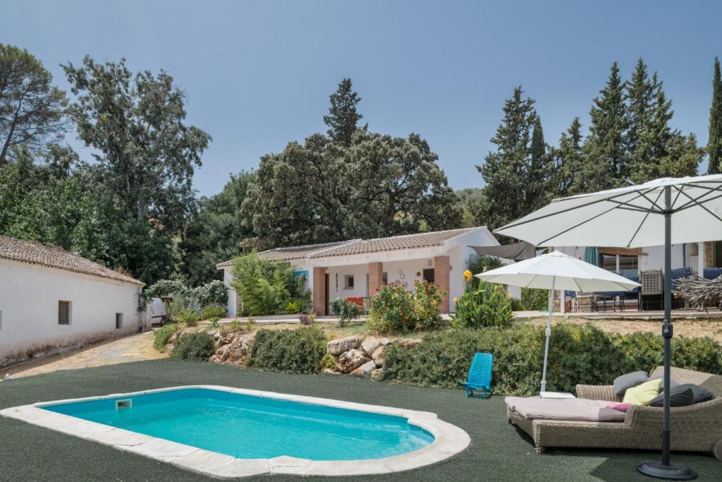 a house with a swimming pool and an umbrella at Finca El Porvenir in El Gastor